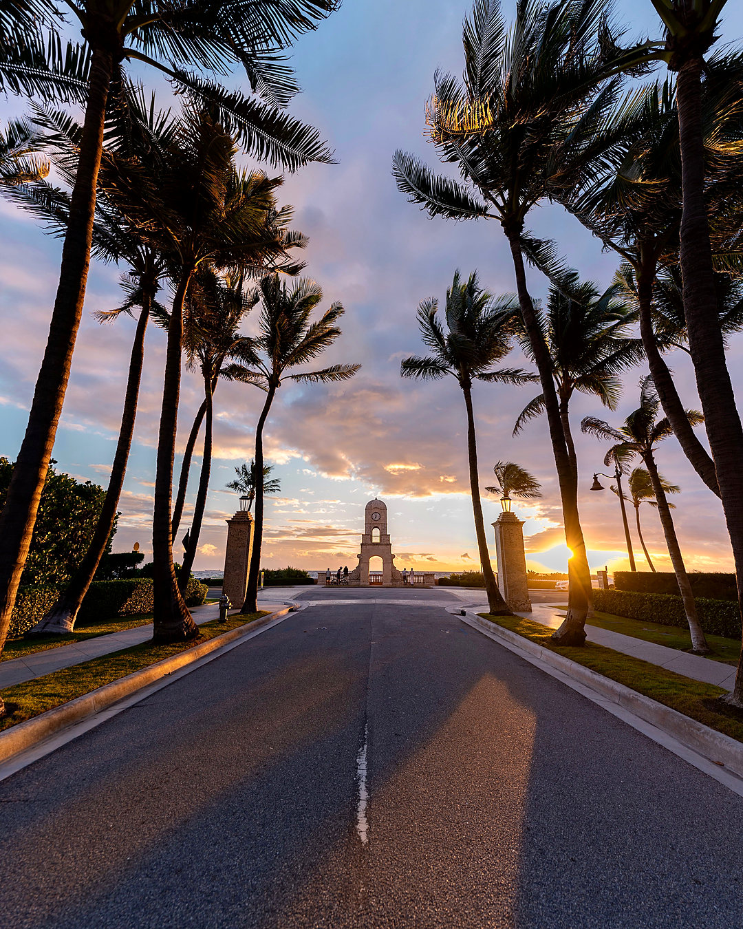 Palm-lined road toward Worth Avenue in Palm Beach at sunset